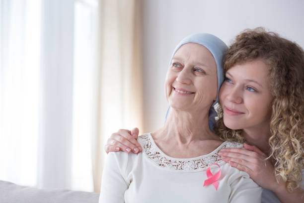 Smiling caregiver hugging senior woman Smiling caregiver hugging senior woman with cancer and pink ribbon bare bosom pic stock pictures, royalty-free photos & images