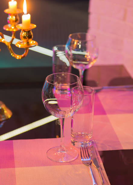 istock Glasses and a candlestick on a glass table in a restaurant. Romantic setting 959915722