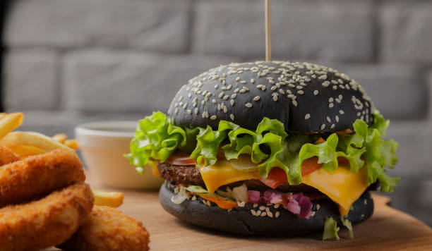 istock Black burger on a wooden background with potatoes and sauce 959918032
