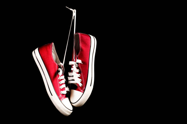 istock Red sneakers hanging on black background 959918114