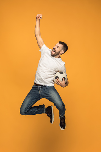 El joven como jugador de fútbol de fútbol pateando la pelota en el estudio photo