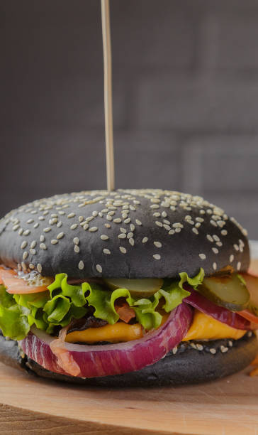 istock Black burger on a wooden background with potatoes and sauce 959922866