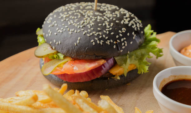 istock Black burger on a wooden background with potatoes and sauce 959923184