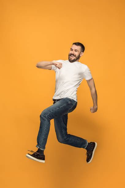 istock Freedom in moving. handsome young man jumping against orange background 959924052