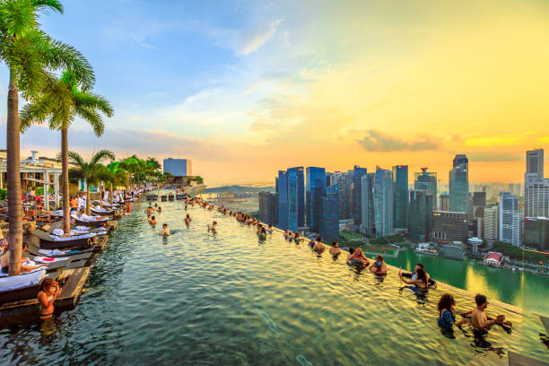 Infinity Pool Singapore Singapore - May 3, 2018: Infinity Pool at sunset of Skypark that tops the Marina Bay Sands Hotel and Casino from rooftop of La Vie Club Lounge on 57th floor. Financial district skyline on background. singapore city stock pictures, royalty-free photos & images
