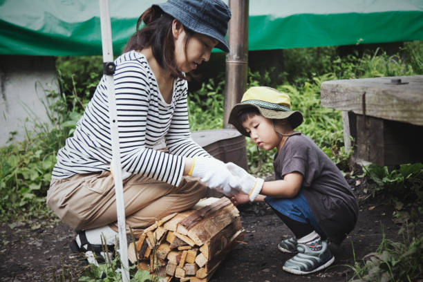 An asian mother helping his son wearing gloves before they untie firewood at camping site..
