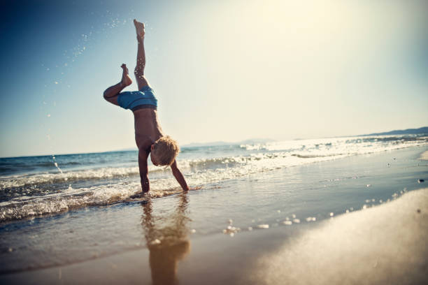 istock Little boy standing on hands on beach 959927318