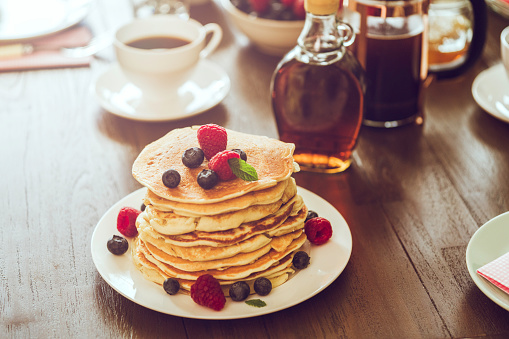 Stack of Pancakes with Maple Syrup, Berries and Fresh Coffee for breakfast