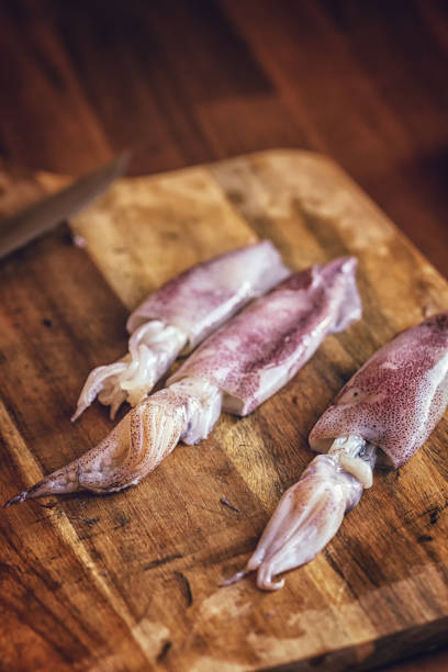 istock Cleaning and Cutting Fresh Squid on a Wooden Cutting Board 959928152