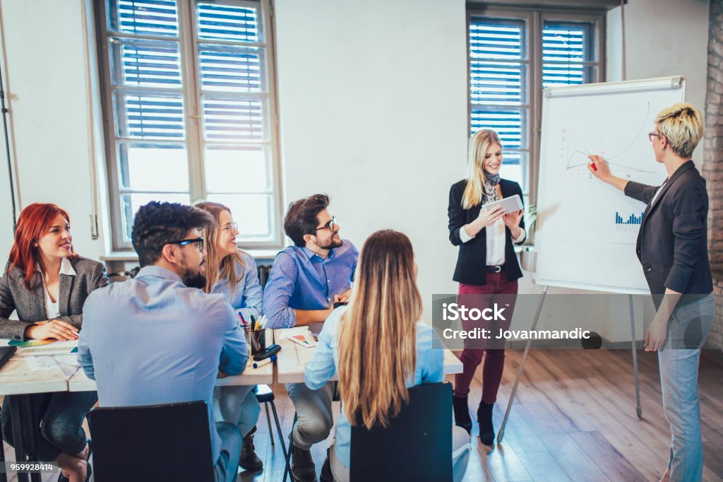 Businesswomen At Whiteboard Giving Presentation In Boardroom Education Training Class Stock Photo