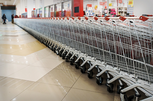 Many empty shopping carts in a row. Inside a large supermarket. Modern and stylish shopping Mall. Grocery store