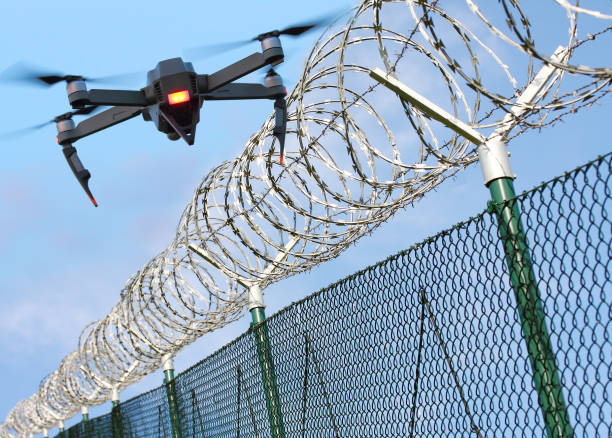 Drone monitoring barbed wire fence on state border or restricted area. Drone monitoring barbed wire fence on state border or restricted area. Modern technology for security. Digital artwork with fictive vehicle. barbed wire photos stock pictures, royalty-free photos & images