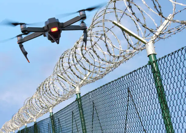 Drone monitoring barbed wire fence on state border or restricted area. Modern technology for security. Digital artwork with fictive vehicle.