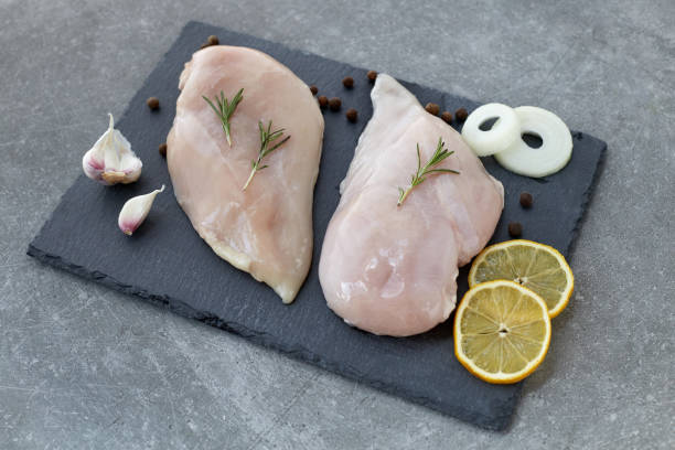 raw chicken breast fillet with spices, garlic and rosemary on a grey stone table. healthy food. - garlic chicken breast raw chicken imagens e fotografias de stock
