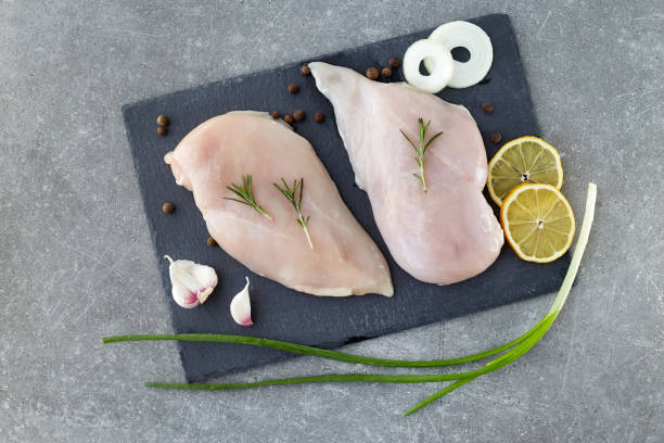 raw chicken breast fillet with spices, garlic and rosemary on a grey stone table. top view. healthy food. - garlic chicken breast raw chicken imagens e fotografias de stock