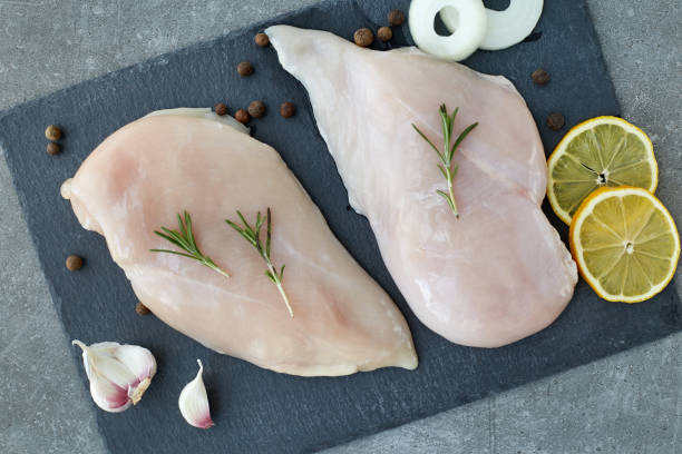 raw chicken breast fillet with spices, garlic and rosemary on a grey stone table. top view. healthy food. - garlic chicken breast raw chicken imagens e fotografias de stock