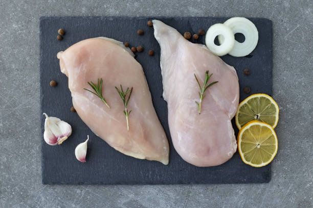 raw chicken breast fillet with spices, garlic and rosemary on a grey stone table. top view. healthy food. - garlic chicken breast raw chicken imagens e fotografias de stock