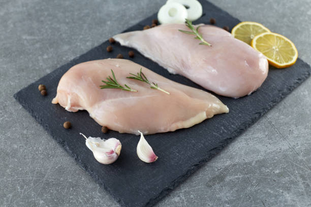 raw chicken breast fillet with spices, garlic and rosemary on a grey stone table. healthy food. - garlic chicken breast raw chicken imagens e fotografias de stock