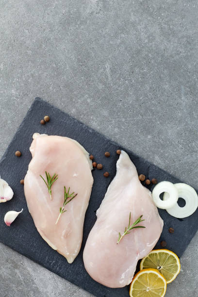 raw chicken breast fillet with spices, garlic and rosemary on a grey stone table. top view. healthy food. - garlic chicken breast raw chicken imagens e fotografias de stock