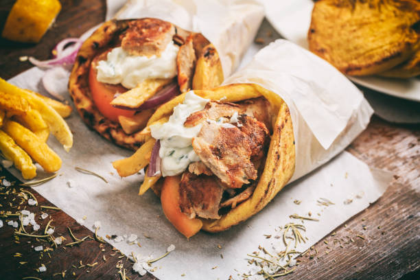 greek gyros wraped in a pita bread on a wooden background - souvlaki imagens e fotografias de stock