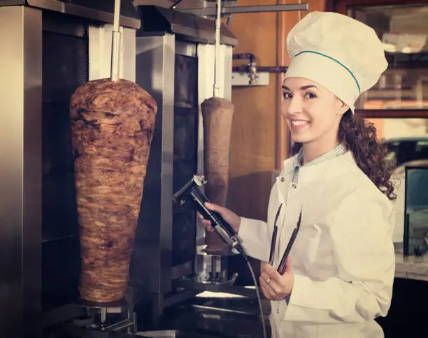 Photo of Female chef cutting meat for shawarma