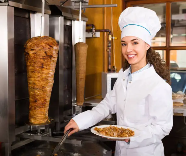 Photo of Female chef cutting meat for shawarma