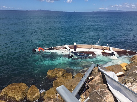 Sailing boat crashed on rocks in te sea