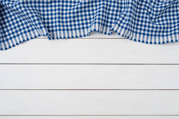 istock Blue checkered tablecloth on an old wooden table. Close up 959942892