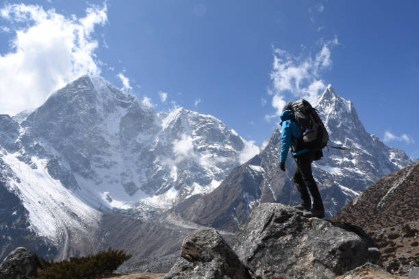 Trekker on the Everest Base Camp Trek in front of Mount Cholache and Mount Tabuche stock photo