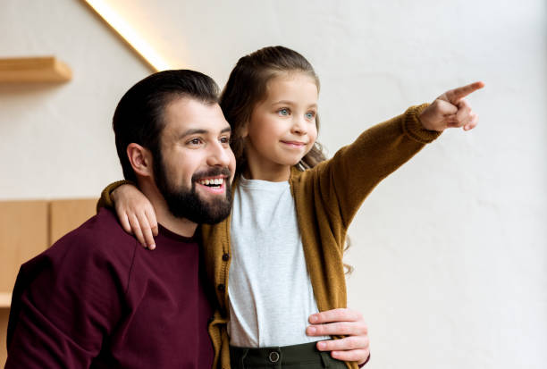 istock happy daughter pointing on something and hugging father 959952000