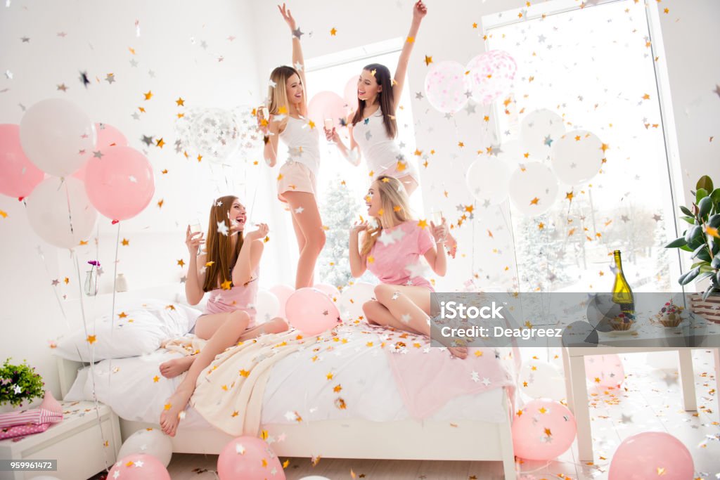 Cheerful, cool, sexy, pretty, charming, funky girls in night wear enjoying rain of colorful stars, confetti having theme party meeting indoor, drinking alcohol, dancing, laughing Party - Social Event Stock Photo