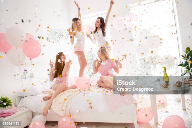 Cheerful Cool Sexy Pretty Charming Funky Girls In Night Wear Enjoying Rain Of Colorful Stars Confetti Having Theme Party Meeting Indoor Drinking Alcohol Dancing Laughing Stock Photo - Download Image Now