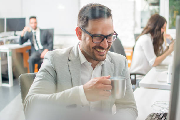 istock Smiling business man drinking coffee during office break. 959970364