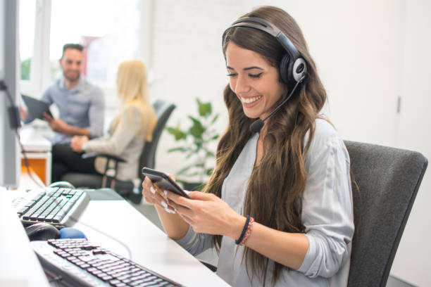 istock Smiling young woman with headset using mobile phone in office 959970726