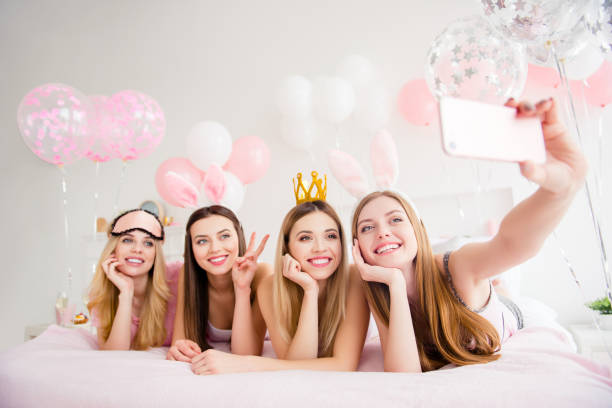 Cheerful, joyful, charming, pretty, funny, dreamy, cute models lying on bed shooting self portrait on front camera, holding using smart phone, showing two fingers, peace symbol, enjoying theme party alegre, alegre, encantador, bonita, divertidos, soñadoras, lindos modelos en lecho de disparos retrato del uno mismo en la cámara frontal, que usando el teléfono inteligente, mostrando dos dedos, símbolo de la paz, disfrutando de la fiesta temática
