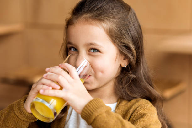 adorable kid drinking orange juice in cafe and looking at camera adorable kid drinking orange juice in cafe and looking at camera juice drink stock pictures, royalty-free photos & images