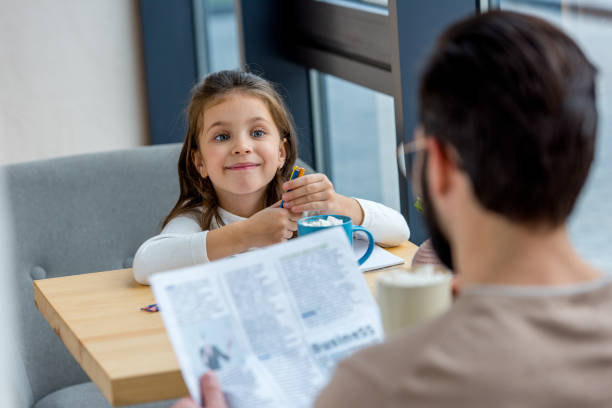 istock father reading business newspaper while daughter drawing in cafe 959974100