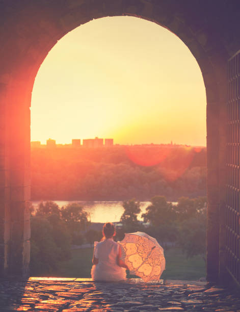 Beautiful little princess with sunshade enjoying at sunset on the Kalemegdan fortress in Belgrade, Serbia