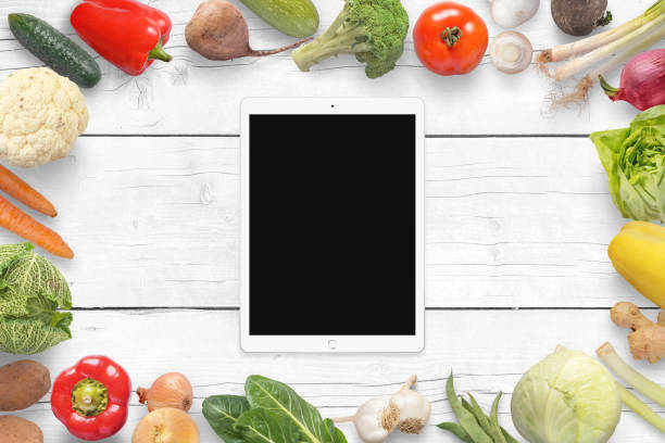 istock Tablet and vegetables on wihite wooden desk. Top view. 959987390