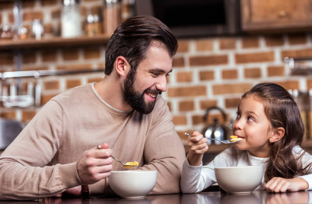 istock smiling father and daughter eating breakfast and looking at each other 959989480