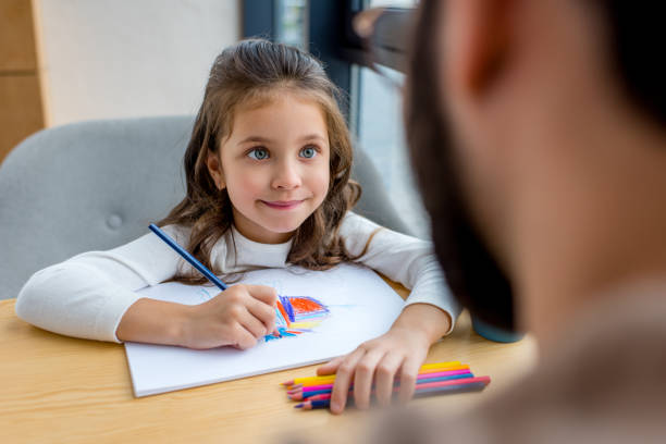 istock cropped image of daughter drawing and looking at father 959989898