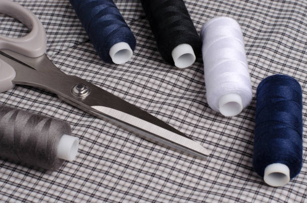 Tools and accessories for sewing. Sewing thread, scissors  on gray textile background. Close up