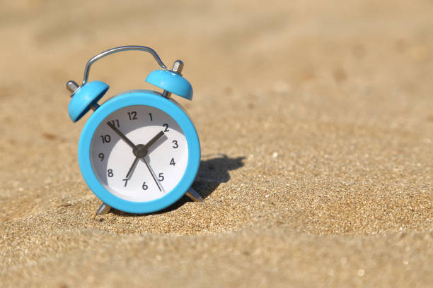 istock Vacation time. Alarm clock on the sand 960005412