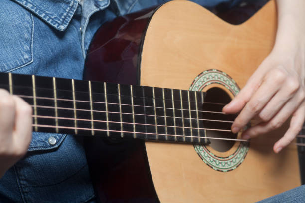 istock Young womans hands playing a acoustic classic guitar 960012664
