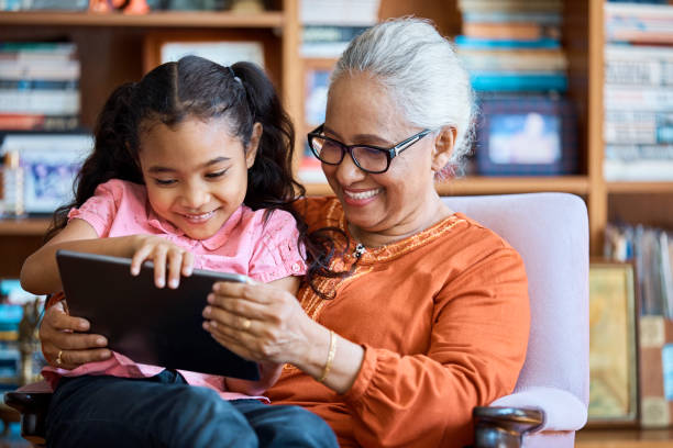 istock Smiling grandmother using digital tablet with girl 960012936
