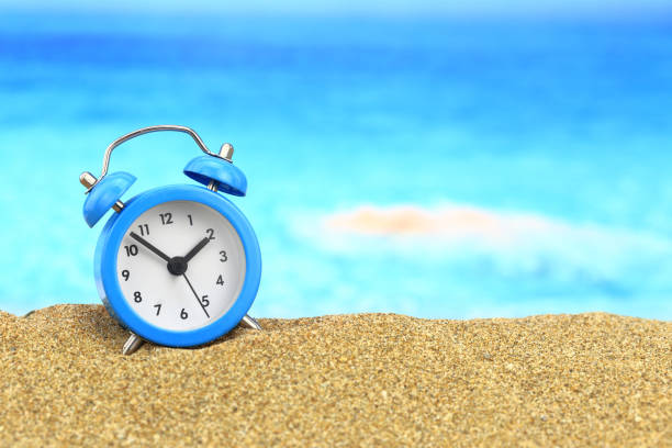 istock Vacation time. Alarm clock on the sand 960013440