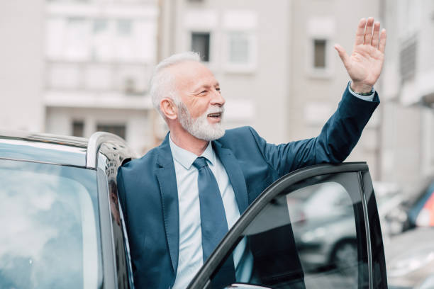 istock Elderly businessman waving hand while entering car 960016870
