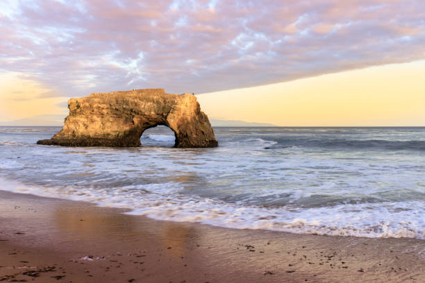 最後の残りの自然なアーチに沈む夕日。 - monterey bay ストックフォトと画像