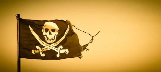 A damaged pirate flag during a strong windy day, with copyspace
