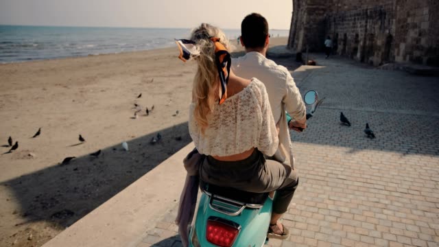 Tourists couple on summer vacations riding scooter on Mediterranean island